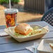 A sandwich and a drink on a EcoChoice rectangular tray with a plastic cup of brown liquid and ice.