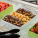 A table with a G.E.T. Enterprises white resin-coated aluminum square bowl filled with chocolate-covered donuts.