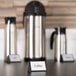 An American Metalcraft black wood table tent sign that says "Coffee" on a table with coffee containers.