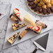 A white G.E.T. Enterprises triangle disc with a slice of cheesecake with chocolate chips on top.