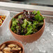 A G.E.T. Enterprises Bugambilia terracotta resin-coated aluminum bowl filled with salad on ice.