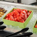 A lime G.E.T. Enterprises Bugambilia salad bowl filled with watermelon cubes on a tray of fruit.