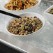 A white G.E.T. Enterprises resin-coated aluminum bowl filled with pasta and vegetables on a counter.