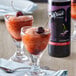 A glass of cherry-infused drink with ice and a cherry on top.