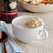 A bottle of DaVinci Gourmet Classic Cake Batter flavoring syrup with a cup of coffee with whipped cream and a spoon.