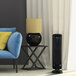 A black Fellowes AeraMax 90 air purifier on a table next to a blue chair.