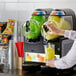 A woman pouring yellow juice into a Vollrath dual frozen beverage machine.