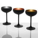 Three Stolzle Glisten matte black and copper coupe glasses on a white surface.