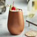 a copper cup with a cherry and ice cubes