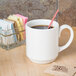 A white Homer Laughlin china mug with a straw in it.