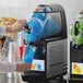 A person pouring blue liquid into a Vollrath frozen beverage machine.