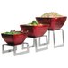 A group of red bowls of food on Vollrath stainless steel square bent buffet risers.