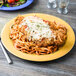 A plate of spaghetti and chicken with cheese and pasta on a yellow Diamond Mardi Gras melamine plate.