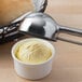 A bowl of butter with a Vollrath stainless steel scoop over it.