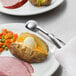 A person using a Vollrath stainless steel disher to scoop food onto a plate.