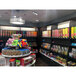 A Rosseto triple dry food dispenser mounted on a shelf in a store with shelves of candy.