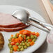 A Vollrath stainless steel squeeze handle disher scoop with a carrot on a plate.