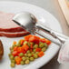 A plate of food with a Vollrath stainless steel squeeze handle disher on top.