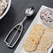 A metal spoon with a spring on a plate of crackers.