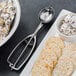 A Vollrath stainless steel oval disher with food in a bowl and a spoon.