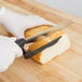 A person using a MercerSlice serrated knife to cut a loaf of bread.