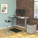 A white and gray rectangular table top on a wood table with a computer and a stool.