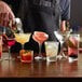 A bartender pouring red liquid into an Acopa Hobnail rocks glass.