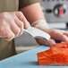 A person using Mercer Culinary fish bone tongs to cut a piece of salmon.