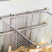 A Cecilware fryer basket with a wire front hook holding a basket of french fries.