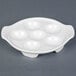 A white plate with six egg-shaped holes.