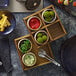 A Playground Ananti walnut wood square tray with stand holding a variety of food items on a table.