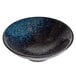 A white stoneware bowl with blue and black speckles.
