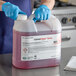 A person in blue gloves holding a plastic container with a label for Convotherm ConvoClean Solution.