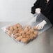 A woman in gloves holding a LK Packaging heavy-duty plastic food bag filled with potatoes.