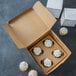 A Baker's Mark kraft cupcake box with cupcakes in it with a white background.
