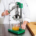 A person using a Garde rubber lever cover to juice oranges.