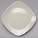 A close-up of a Tuxton eggshell square china plate on a gray surface.
