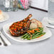 A Tuxton eggshell square china plate with meat and vegetables on a table.