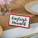 A maroon ceramic table tent with a decal border and the name Kayleigh Howard on it.