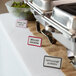 A maroon ceramic table tent with a decal border on a buffet table.