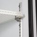 A white metal shelf with a metal clip on it.
