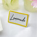 A yellow ceramic table tent sign with a yellow border on a white table.