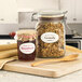 A wooden spoon next to a jar of granola on a cutting board.