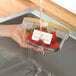 A hand holding a container of strawberries with Avery rectangle white labels.