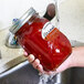 A hand using Avery Oval Dissolvable Labels on a jar of red sauce.