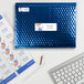 A blue envelope with a white Avery 1 1/3" x 4" mailing label next to a keyboard.