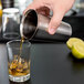 A person using a Vollrath stainless steel tumbler to pour a cocktail.