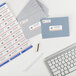 A white desk with a keyboard, mouse, and Avery White Mailing Address Labels on envelopes.