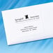 A white envelope with black text and a white Avery shipping label with black text on it.