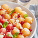 A bowl of cantaloupe with mint leaves and pomegranate seeds.